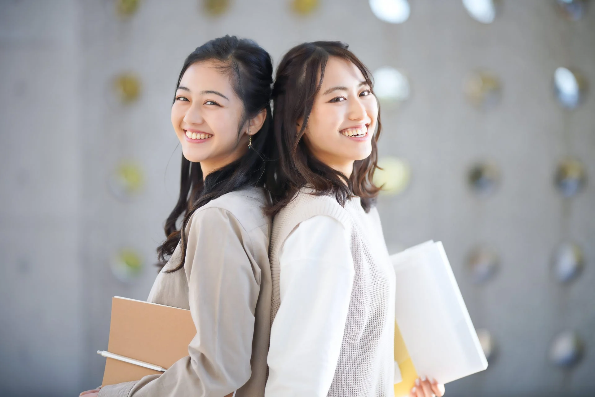 笑顔で背中合わせに立つ2人の女性