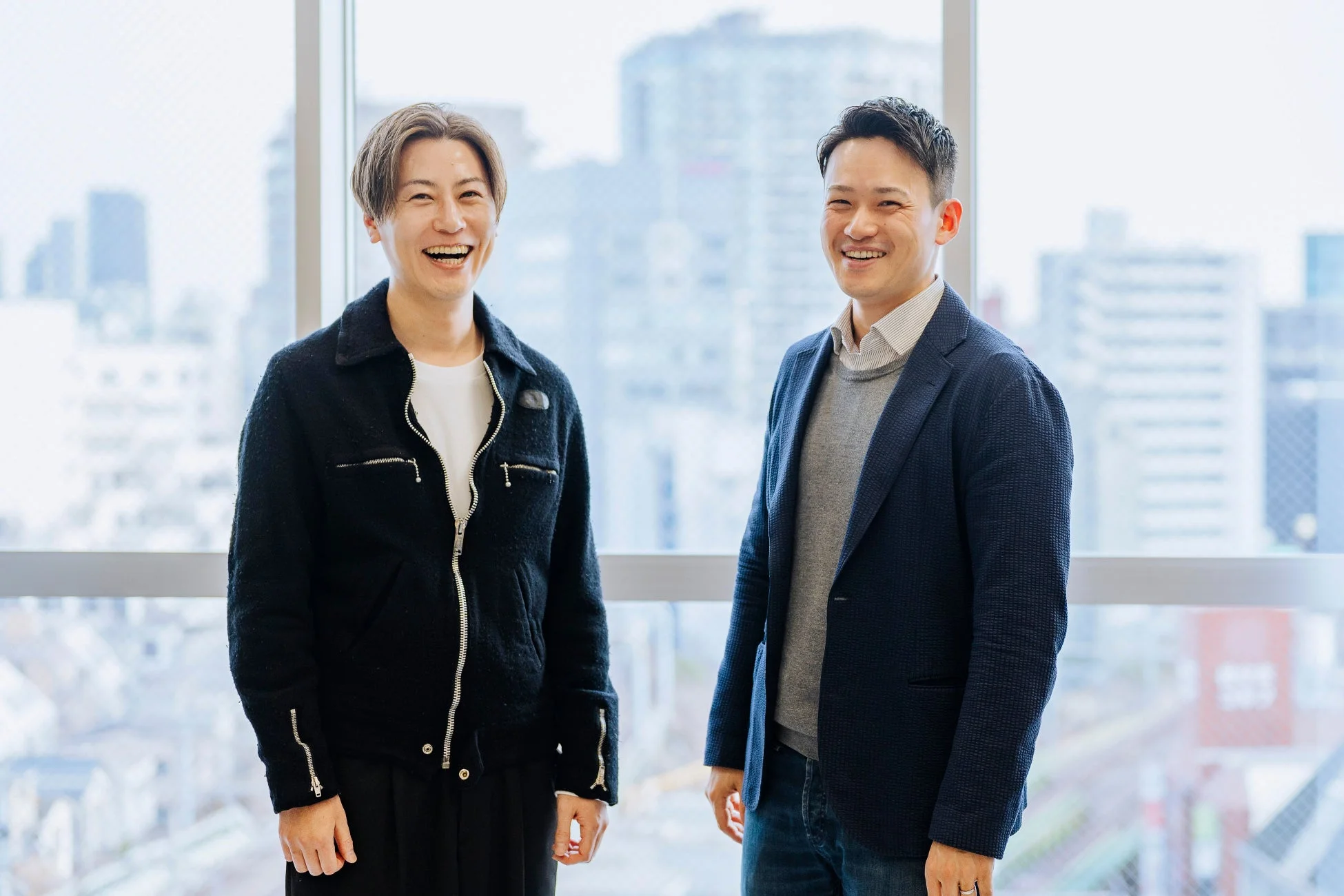 オフィスで笑顔で並び立つ2人の男性