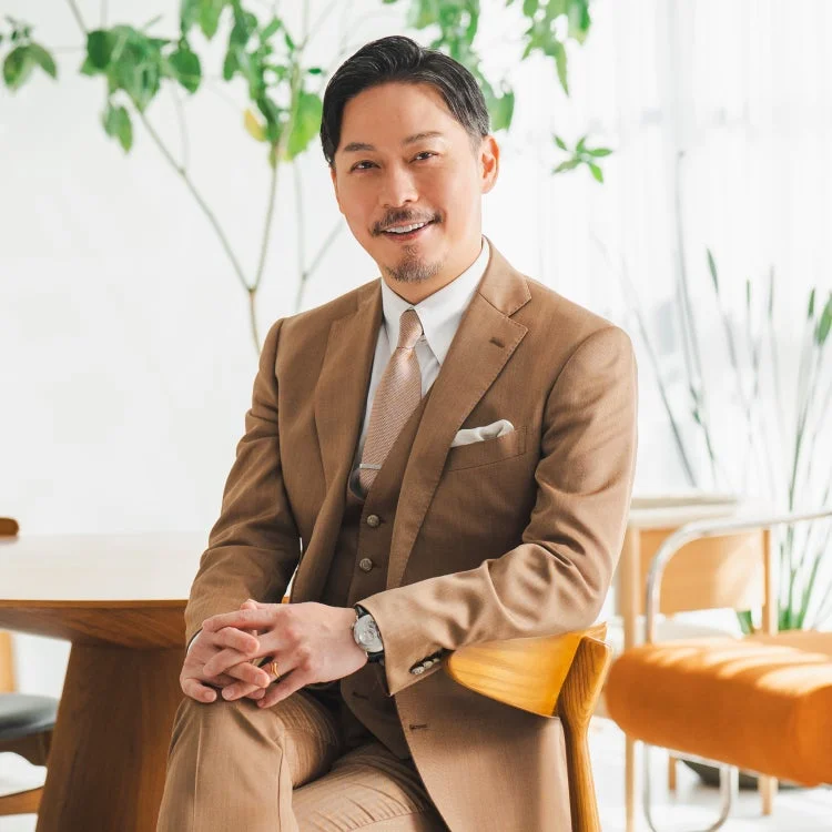 茶色のスリーピーススーツを着て微笑む坂東工さん