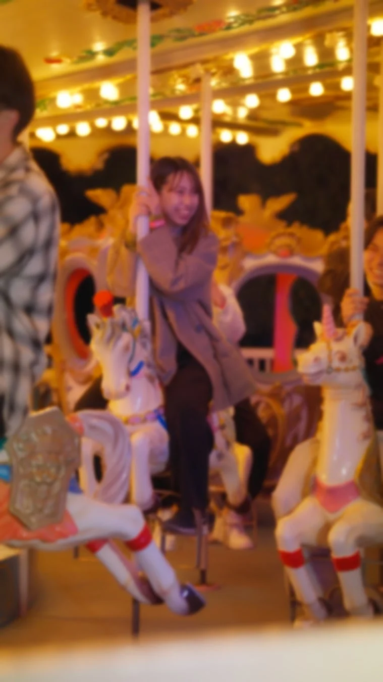 夜のメリーゴーランドに乗って笑顔を見せる女性