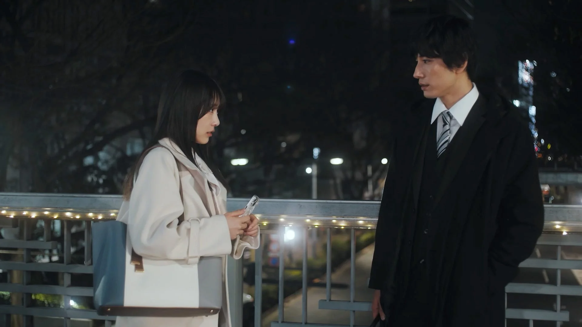 夜の街で男女が橋の上で向かい合って話す