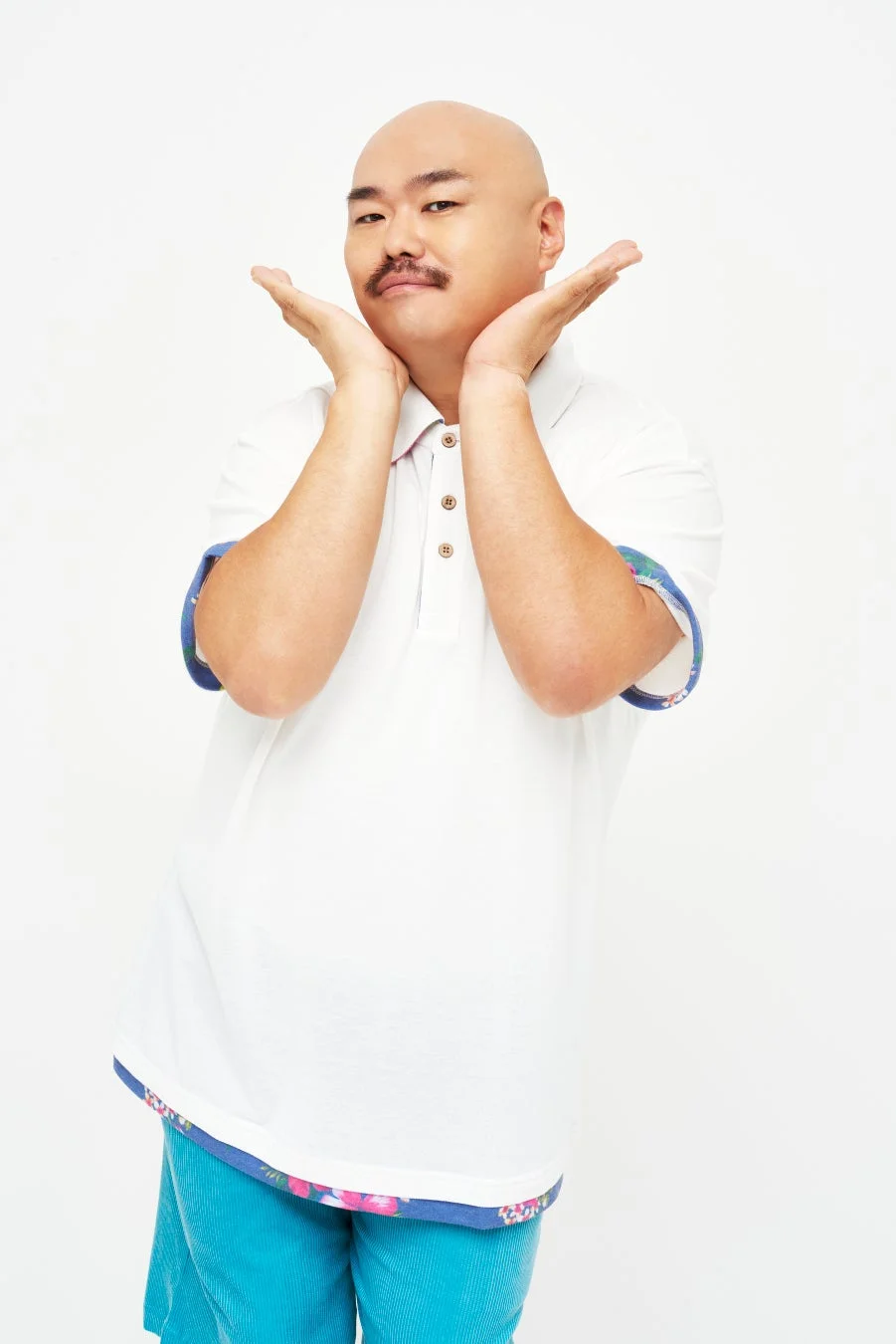 両手で顔を包むようなユーモラスなポーズでカメラに微笑むクロちゃん