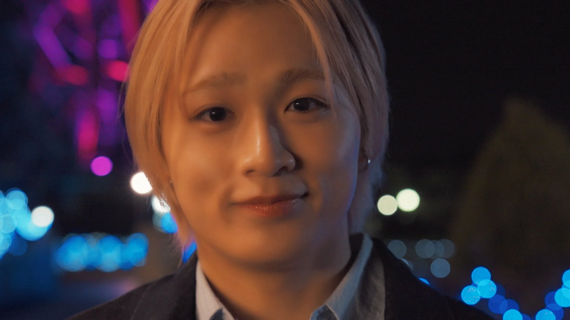 夜のイルミネーションを背景に笑顔の田中笑太郎