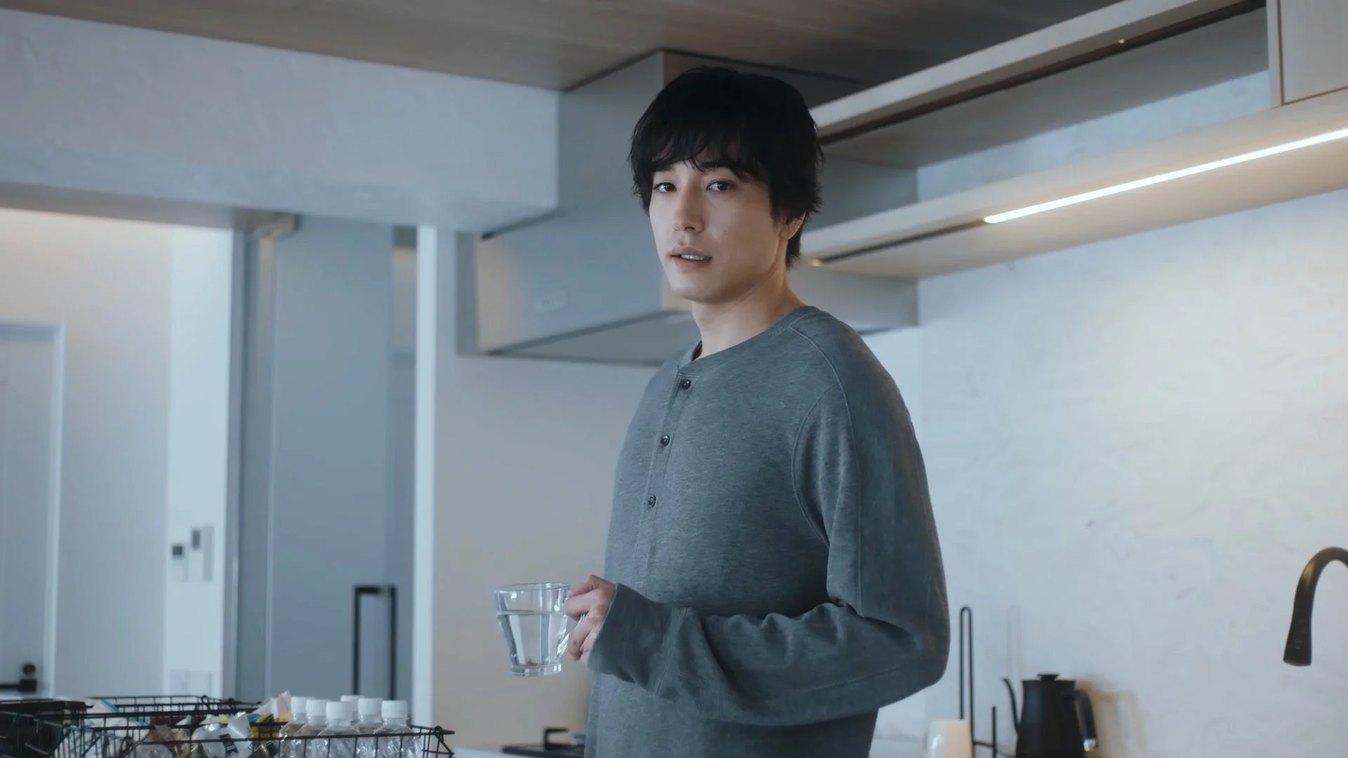 キッチンでグラスに入った水を持つ男性