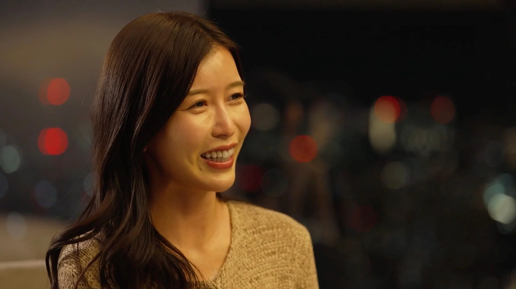 夜の屋外らしき場所で明るい笑顔を見せる女性のポートレート